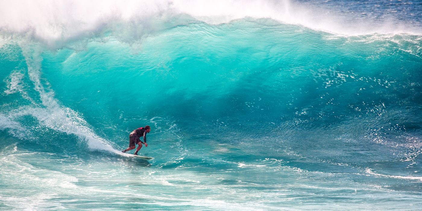 Surfer riding a turquoise breaking wave