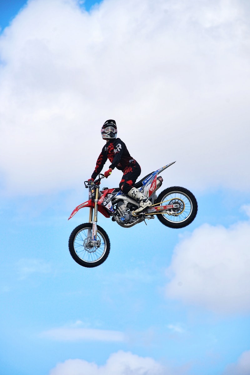 Motocross rider mid-jump against a cloudy sky
