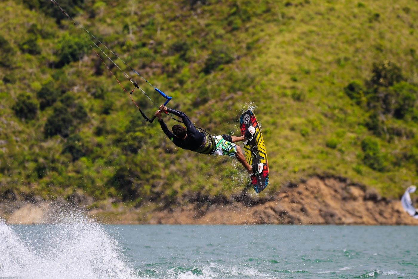 Kiteboarder mid-air over teal water